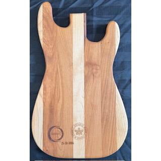 An electric guitar shaped serving board with a wooden texture and an engraved design resembling musical notes.